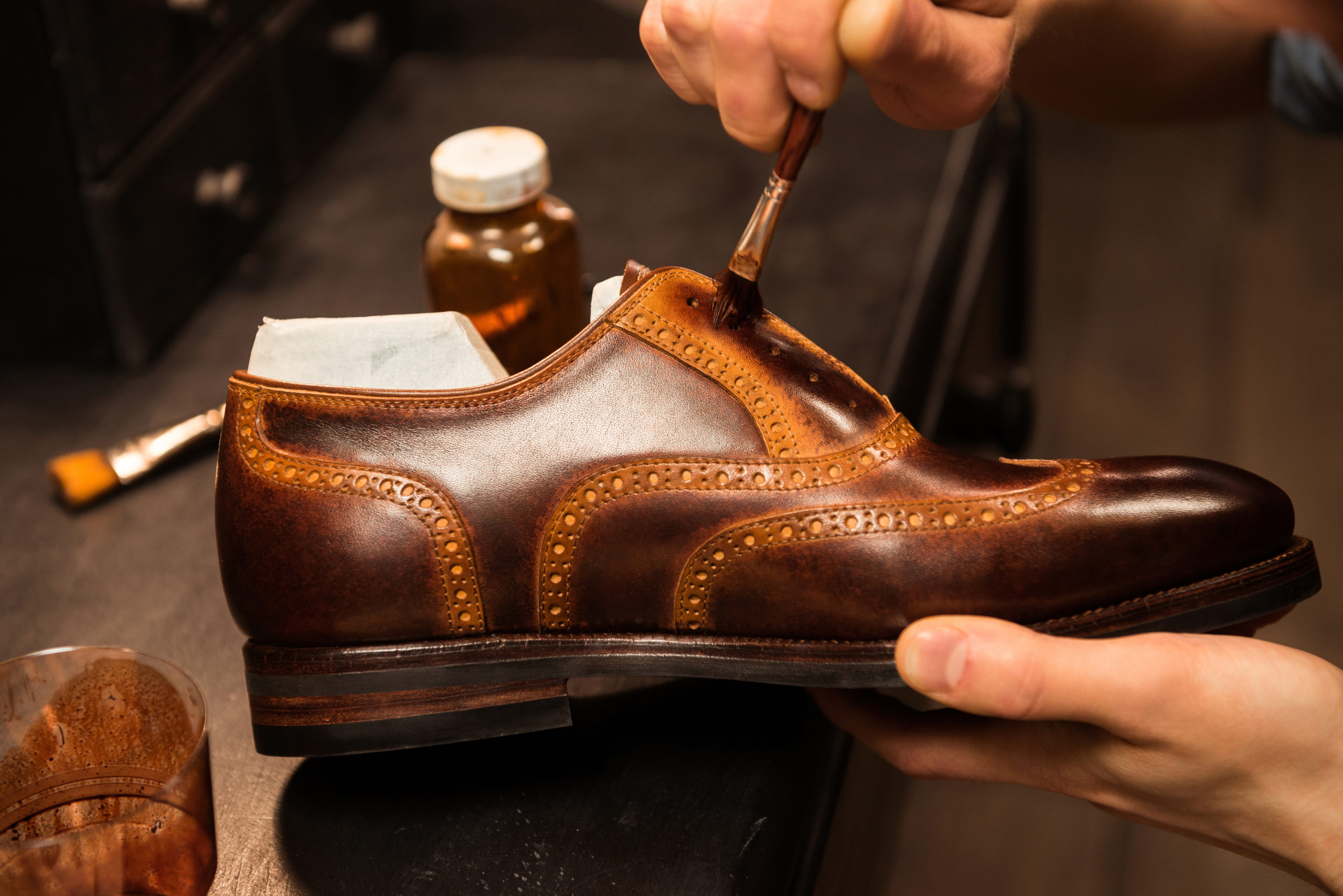 brown shoe being brushed by hand