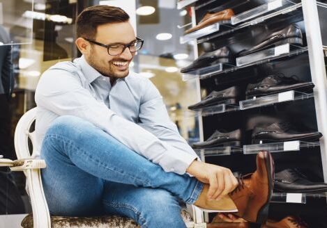 man trying on shoes in a shoe store smiling